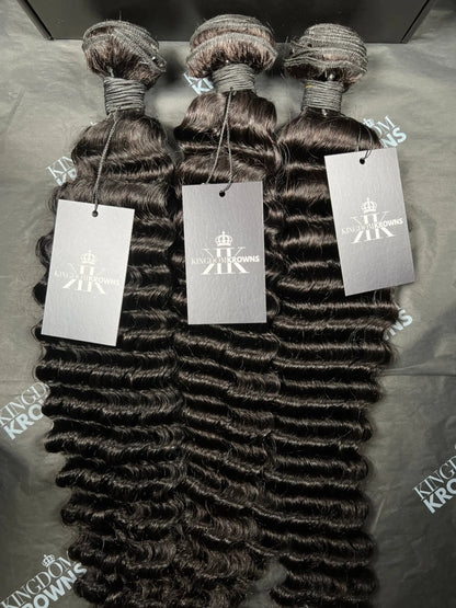 Three bundles of hair extensions with King domKrown labels on a gray surface.