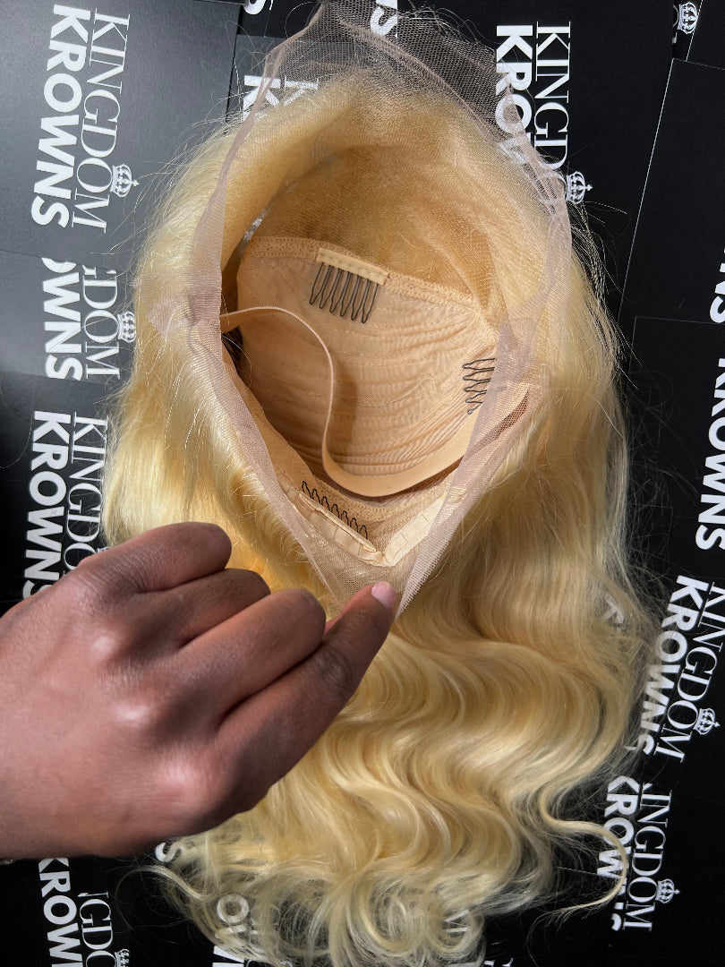 A blonde human hair wig with body wave texture on a white background.