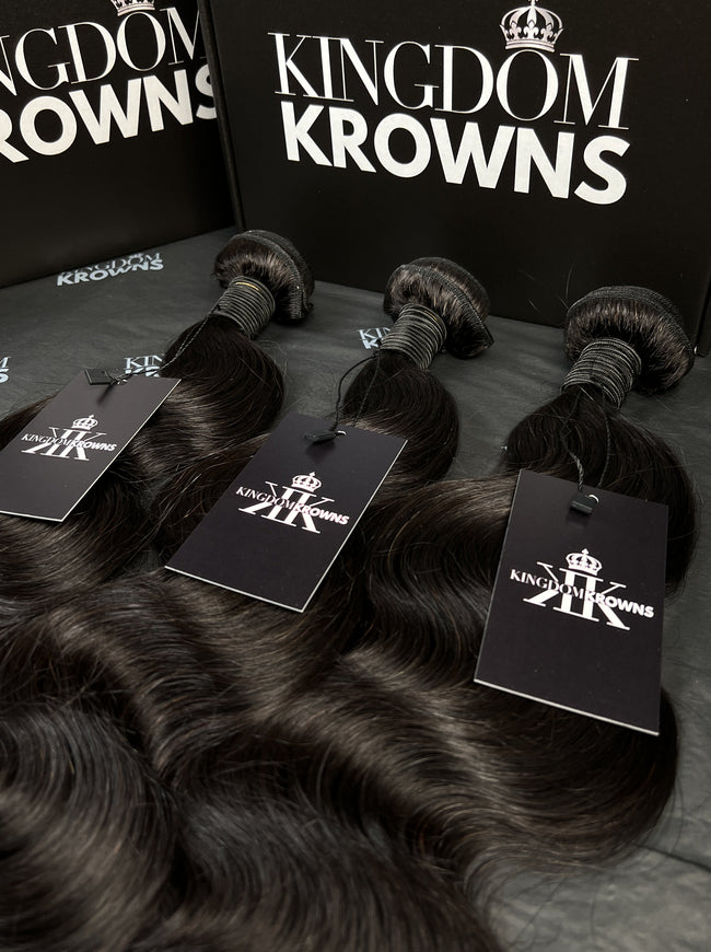 Black hair extensions with 'Kingdom Krowns' packaging on a dark surface