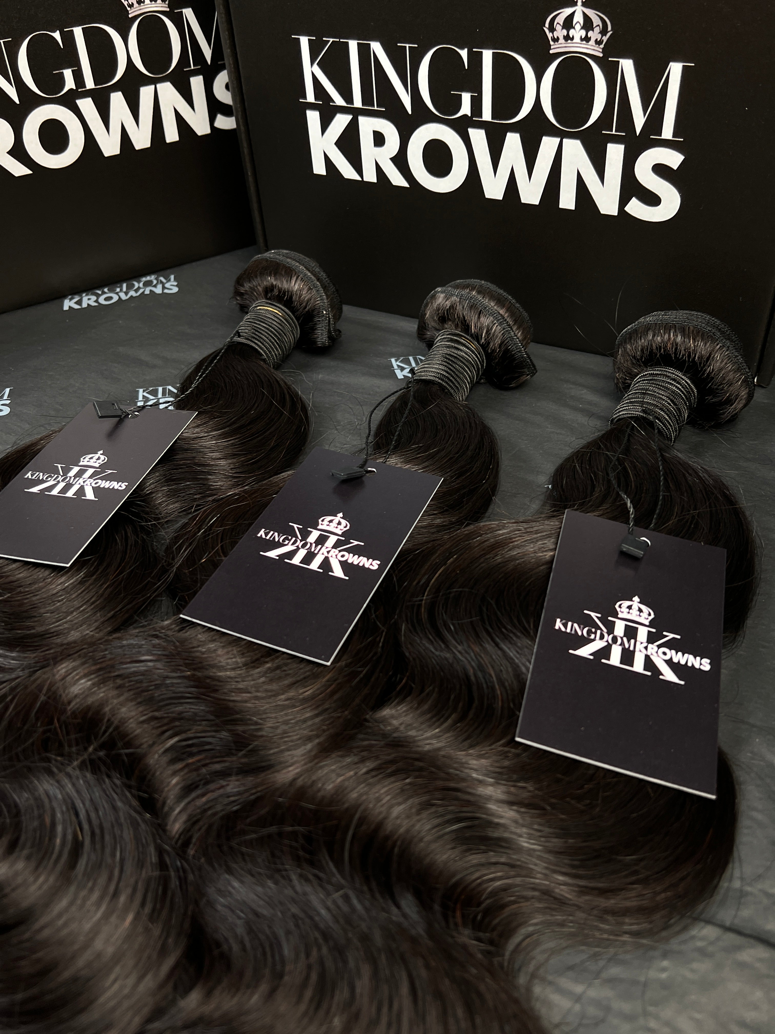 Black hair extensions with 'Kingdom Krowns' packaging on a dark surface