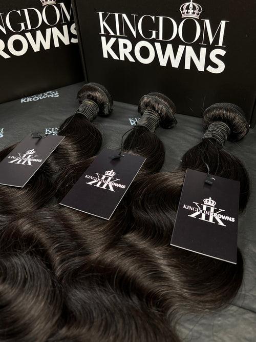 Black hair extensions with 'Kingdom Krowns' packaging on a dark surface