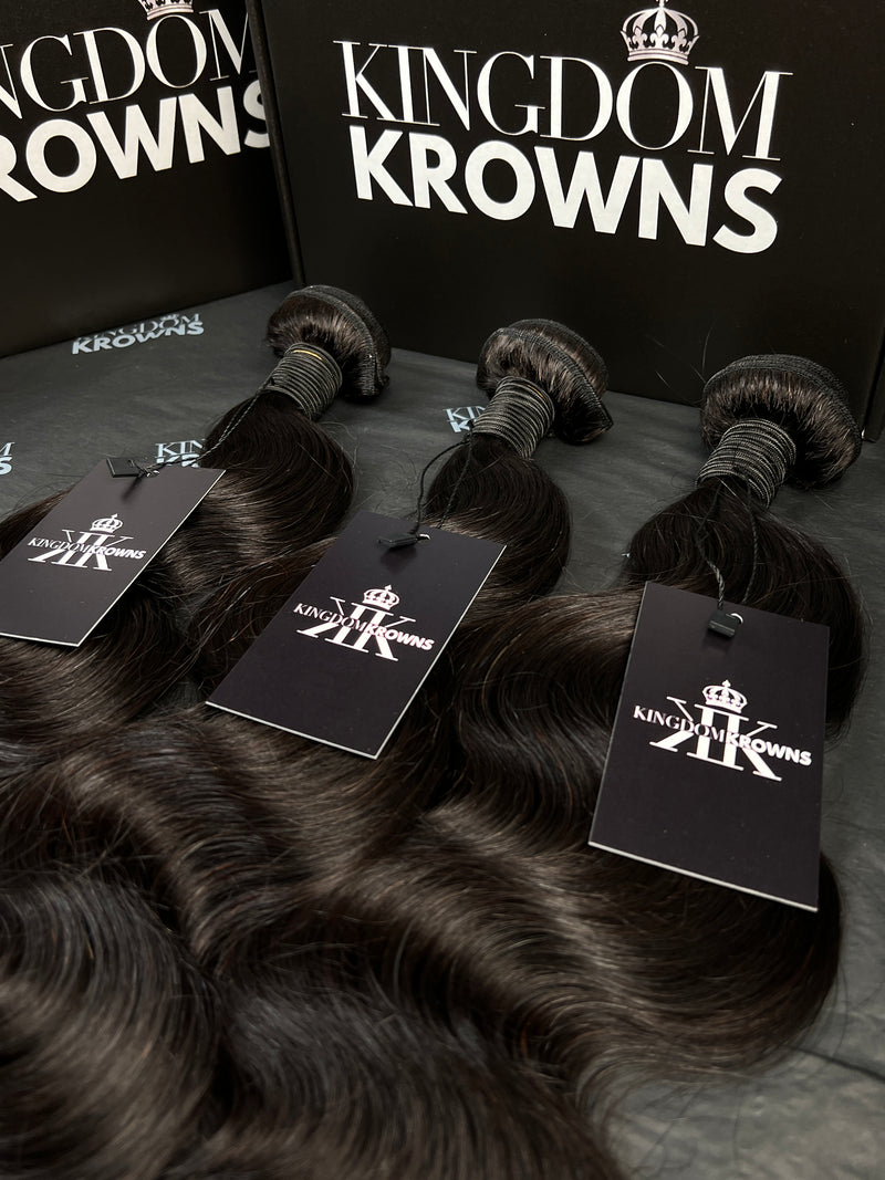 Black hair extensions with 'Kingdom Krowns' packaging on a dark surface