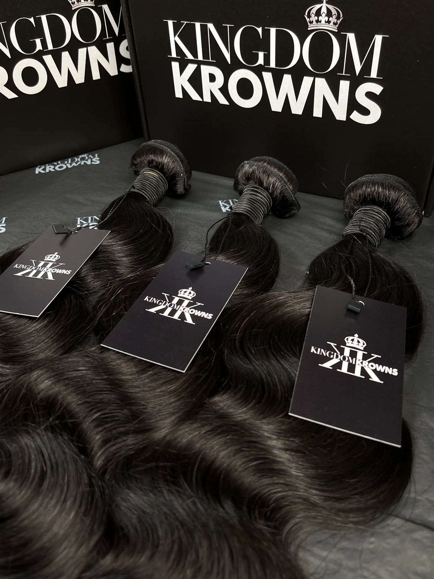 Black hair extensions with 'Kingdom Krowns' packaging on a dark surface