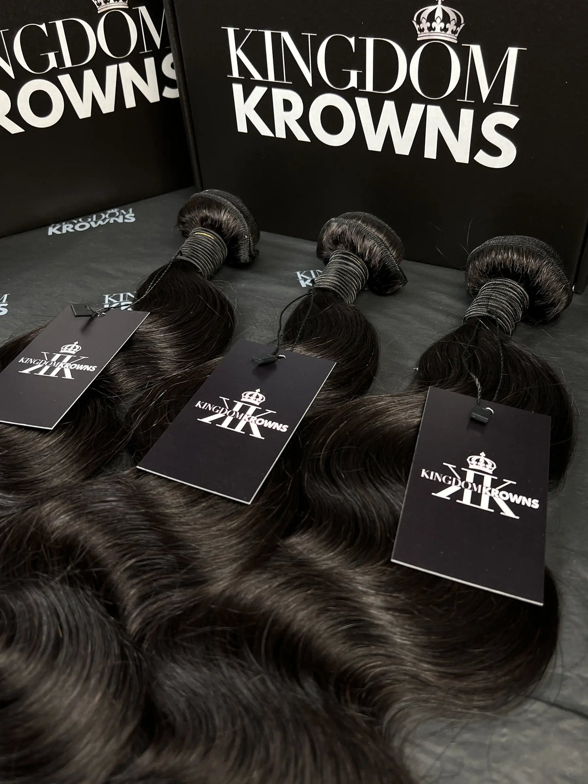 Black hair extensions with 'Kingdom Krowns' packaging on a dark surface