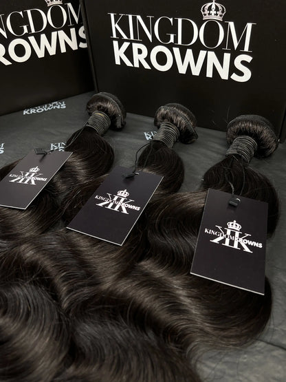 Black hair extensions with 'Kingdom Krowns' packaging on a dark surface
