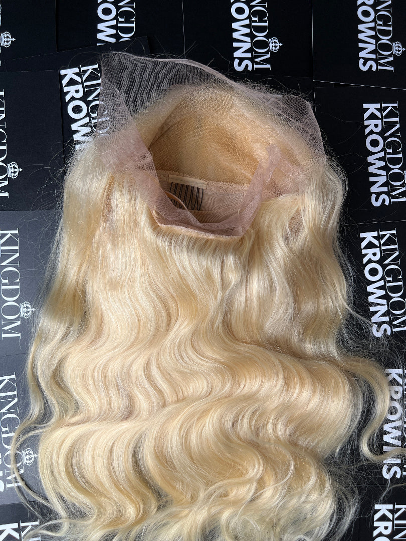 A blonde human hair wig with body wave texture on a white background.