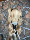 Blonde human hair wig on a mannequin head against a stone wall background