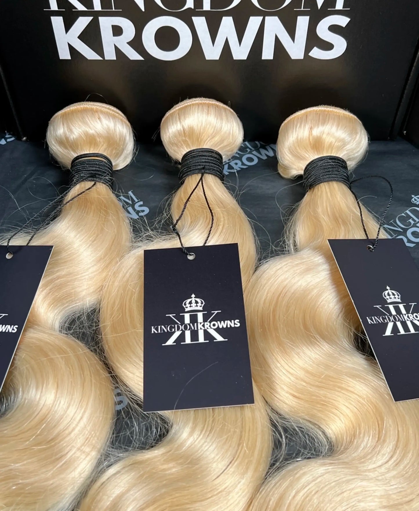 Blonde hair extensions with 'Kingdom Krowns' branding on tags.